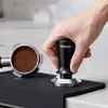 A hand tamping espresso grounds in a portafilter. Produktbild-Vorschau