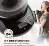 A woman is holding a coffee cup next to a coffee maker with a digital display. Produktbild-Vorschau
