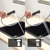 A split image showing a person using a black pull-out kitchen faucet over a black sink. The left side shows a single stream of water, and the right side shows a spray stream. Icons are shown at the bottom of each side. Produktbild-Vorschau