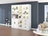 A modern white display cabinet with LED lighting is shown in a living room setting, next to a sofa and a coffee table. Podgląd zdjęcia produktu