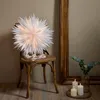 A white paper star decoration with gold accents sits on a wooden chair next to a large mirror and some candles. Podgląd zdjęcia produktu