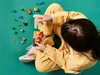 A child is playing with LEGOs on a green background. Podgląd zdjęcia produktu