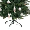 A close-up view of a green artificial Christmas tree decorated with silver ornaments and a black stand. Náhled obrázku produktu