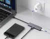 A USB hub is connected to a laptop, an external hard drive, and a power adapter plugged into a wall outlet. Produktbild-Vorschau