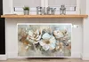 A radiator cover with a floral painting is shown in a room setting, placed on a radiator below a shelf with decorative items. Náhľad obrázku produktu