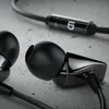 Close-up of black in-ear headphones on a textured gray surface. Produktbild-Vorschau