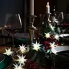 A festive table setting with wine glasses, candles, and decorative star lights. Produktbild-Vorschau