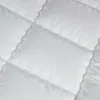 A close-up view of a white quilted blanket or comforter. Produktbild-Vorschau