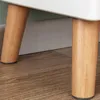 Close-up of the legs of a white shelf unit on a wooden floor. Produktbild-Vorschau