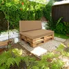 A pallet sofa with beige cushions is placed in a garden setting with lush greenery and gravel. Náhľad obrázku produktu