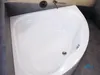 A white corner bathtub in a bathroom with gray tiled walls and floor. Produktbild-Vorschau