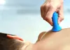 A close-up shot of a person's back with a blue massage tool being applied to their shoulder. Produktbild-Vorschau