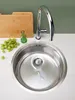 A stainless steel sink with a faucet, a cutting board, and grapes on a white countertop. Produktbild-Vorschau
