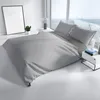A neatly made bed with gray bedding in a bright, modern room with a large window. Produktbild-Vorschau