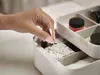 A hand is shown reaching into a makeup organizer to pick up a cotton swab. Náhled obrázku produktu