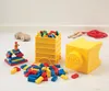 A collection of LEGO storage bricks and building blocks are arranged on a white floor with a white wall in the background. Produktbild-Vorschau