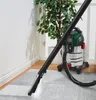 A wet vacuum cleaner is being used to clean a carpet in a room with a plant and white walls. Produktbild-Vorschau