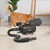 An orange cat is standing next to a black pet dryer in a room. Náhled obrázku produktu