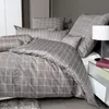 A neatly made bed with gray and white checkered bedding. Produktbild-Vorschau