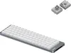 A silver and white low-profile mechanical keyboard is shown from a diagonal angle, with two small, square components with circular elements above it. Produktbild-Vorschau