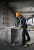 A construction worker is using a circular saw to cut a wooden plank on a construction site. Produktbild-Vorschau