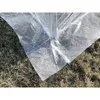 A close-up view of a white greenhouse cover laid out on dry grass. Produktbild-Vorschau