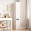 A tall, narrow white cabinet with two doors stands next to a white desk with books and office supplies. Podgląd zdjęcia produktu