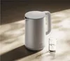 A white electric kettle and a glass of water on a textured surface with dramatic lighting and shadows. Náhľad obrázku produktu