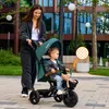 A woman pushing a child on a tricycle in an outdoor urban setting. Produktbild-Vorschau