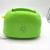 A green toaster with a yellow lever and a smiley sun graphic on a white background. Produktbild-Vorschau