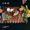 A close-up shot of food preparation on a wooden cutting board, featuring various ingredients and kitchen tools. Produktbild-Vorschau