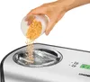 Eine Person schüttet gehackte Walnüsse aus einer kleinen Glasschale in eine Unold Eismaschine One 1, Produktbild-Vorschau