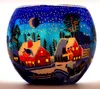 A glass votive holder decorated with a winter village scene under a starry night sky. Produktbild-Vorschau