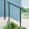 A black handrail is installed on a set of outdoor stairs, with lush green plants in the foreground and a white picket fence and rolling hills in the background. Produktbild-Vorschau