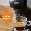 A close-up shot of a black coffee machine brewing espresso into a clear glass mug, with steam rising. Produktbild-Vorschau