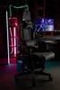 A gaming chair is set up in a room with neon lighting and a computer monitor displaying a colorful graphic. Produktbild-Vorschau