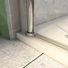 A close-up view of the bottom corner of a shower enclosure, showing the frame and the shower tray. Produktbild-Vorschau