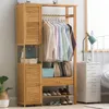A wooden clothing rack with hanging clothes and shoes, next to a white nightstand with a lamp. Náhled obrázku produktu
