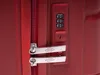 A close-up view of the combination lock and zipper pull tabs on a red suitcase. Podgląd zdjęcia produktu