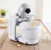 A white kitchen mixer with a whisk attachment is shown on a wooden countertop. Produktbild-Vorschau