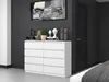 A white dresser with eight drawers is shown in a bedroom setting, with a painting above it and a dark door to the side. Produktbild-Vorschau