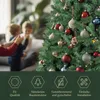 A Christmas tree decorated with ornaments, with two children and a person's hands in the background. Produktbild-Vorschau