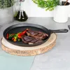 A cast iron skillet with cooked steaks and vegetables on a wooden board. Produktbild-Vorschau