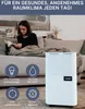 A woman reads a book on a couch next to a white dehumidifier. Produktbild-Vorschau