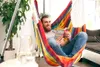 A man is relaxing in a colorful hammock chair while reading a book. Anteprima dell’immagine prodotto