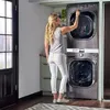 A woman is using a stacked washer and dryer unit in a laundry room. Produktbild-Vorschau