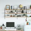 A home office setup with a wall-mounted shelving unit displaying various decorative items and books, a computer monitor, and a mini-fridge. Produktbild-Vorschau