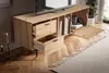 A wooden TV stand with drawers and a cabinet door open, placed in a living room setting with a TV on top and a rug in front. Produktbild-Vorschau