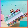 A hand holding a tilted storage container filled with building blocks, with a small building block structure on top. Produktbild-Vorschau