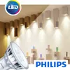 A Philips LED light bulb is shown in the foreground, with a display of modern wall lights in the background. Voir les images du produit